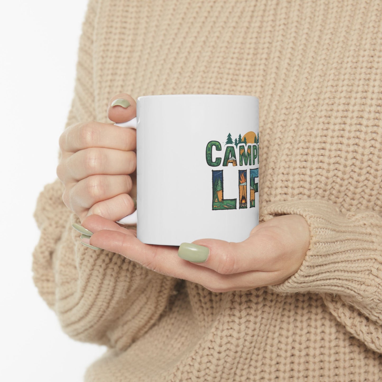 White mug with "CAMPING LIFE" text and forest graphics held by a person.