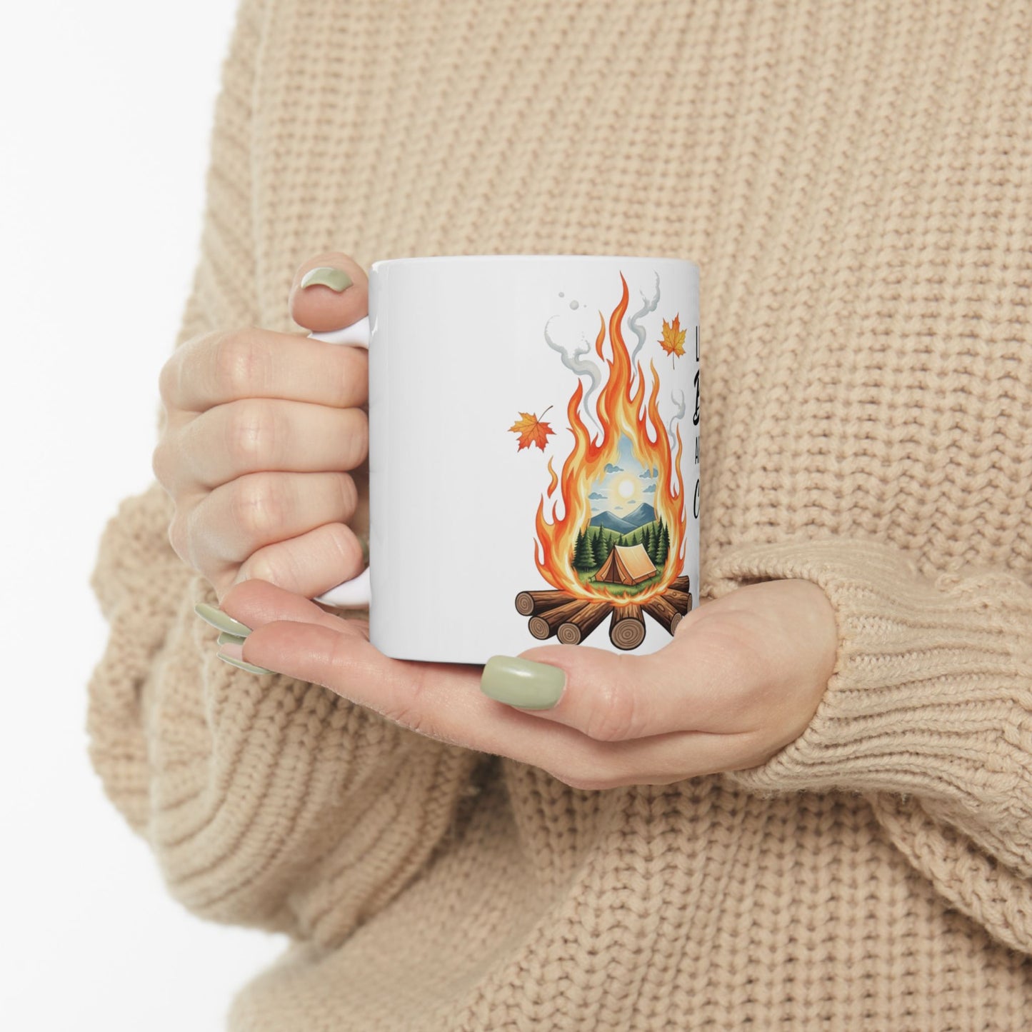 White mug with camping scene and text "Life is better outdoors" held by person.