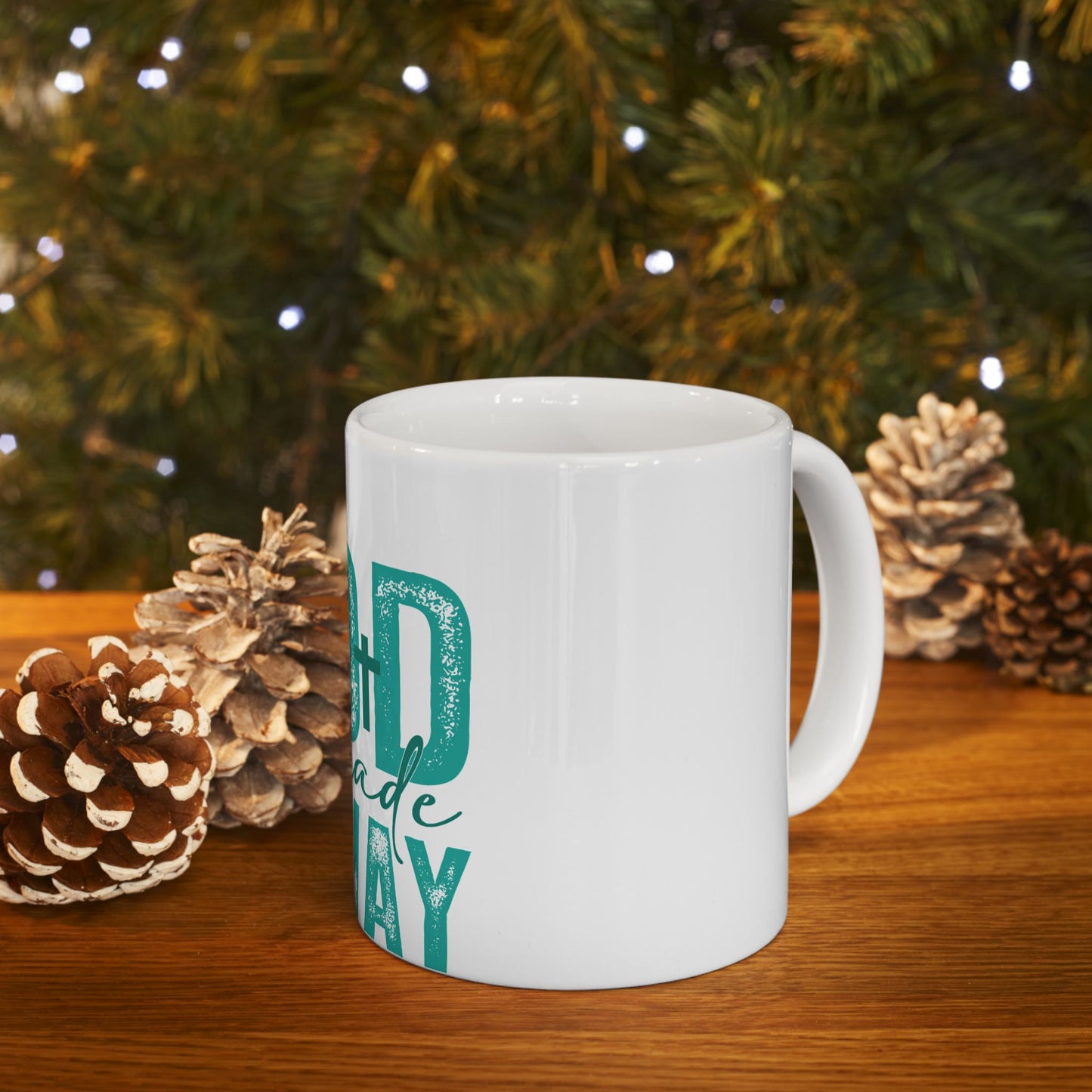 White mug with "Best Dad Ever" text, on a wooden surface with pinecones and holiday lights.