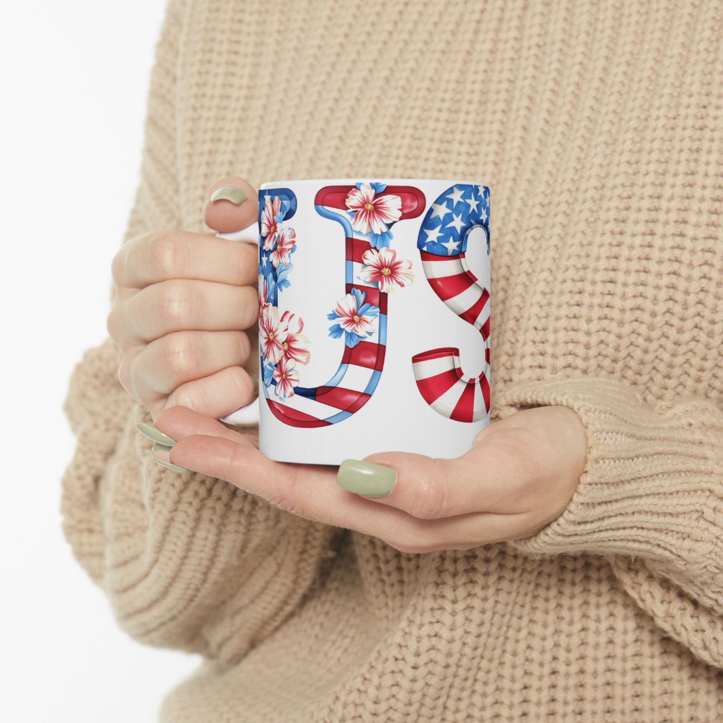 White mug with "US" design in American flag and floral pattern held by hands.