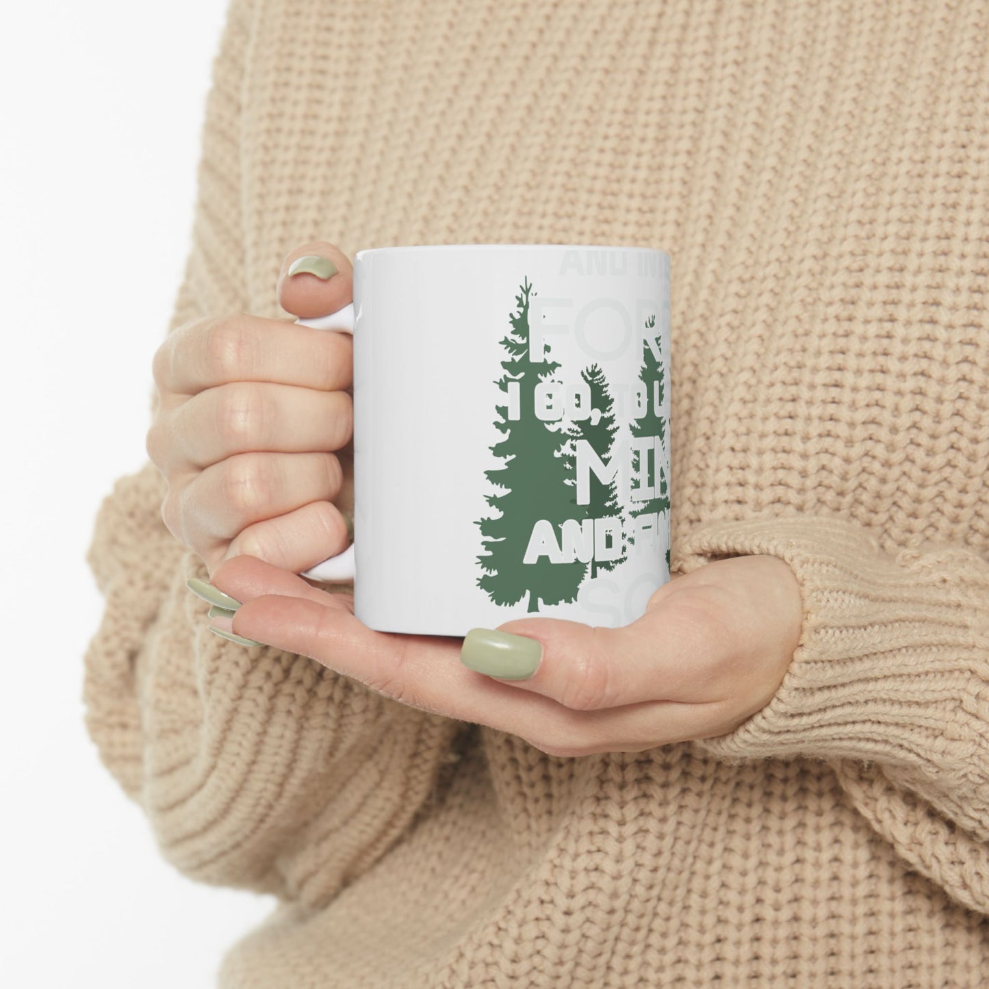 White mug with "Forest vibes" and trees design, held by hands.