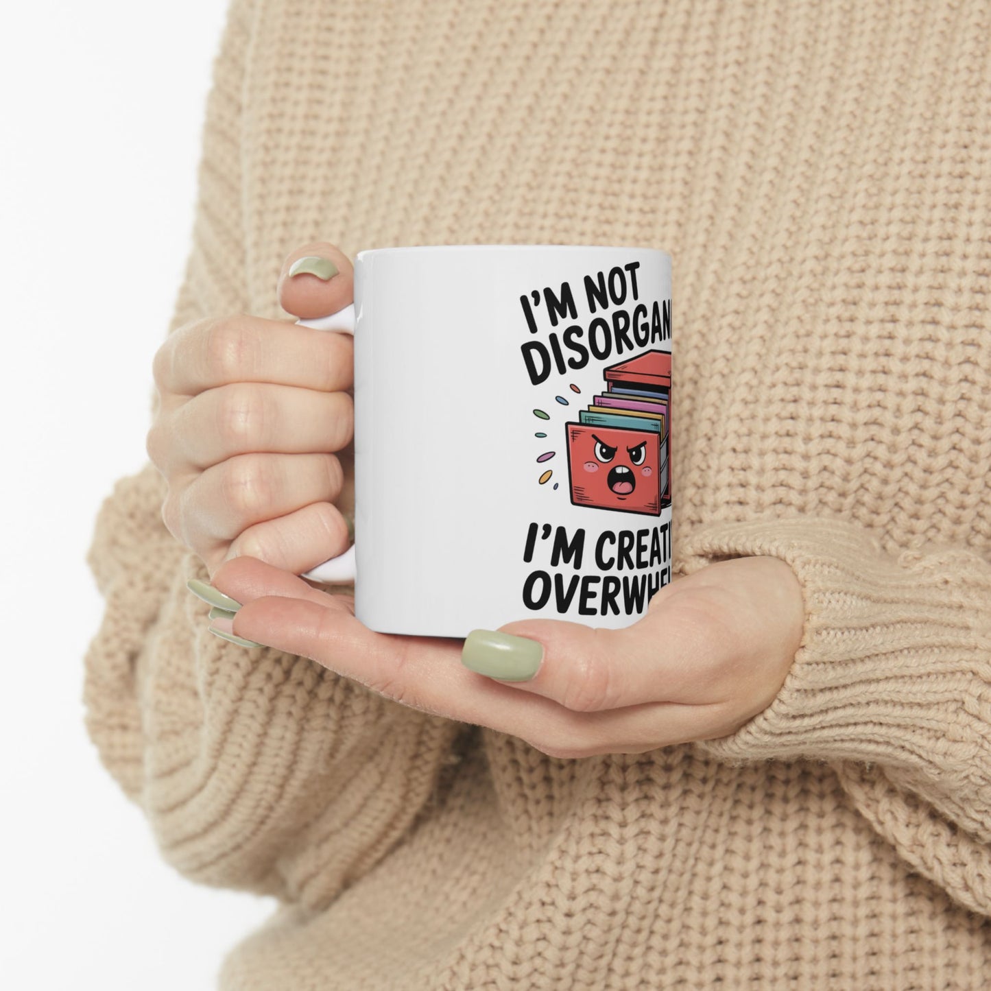 White mug with text "I'M NOT DISORGANIZED I'M CREATIVELY OVERWHELMED" and cartoon books.