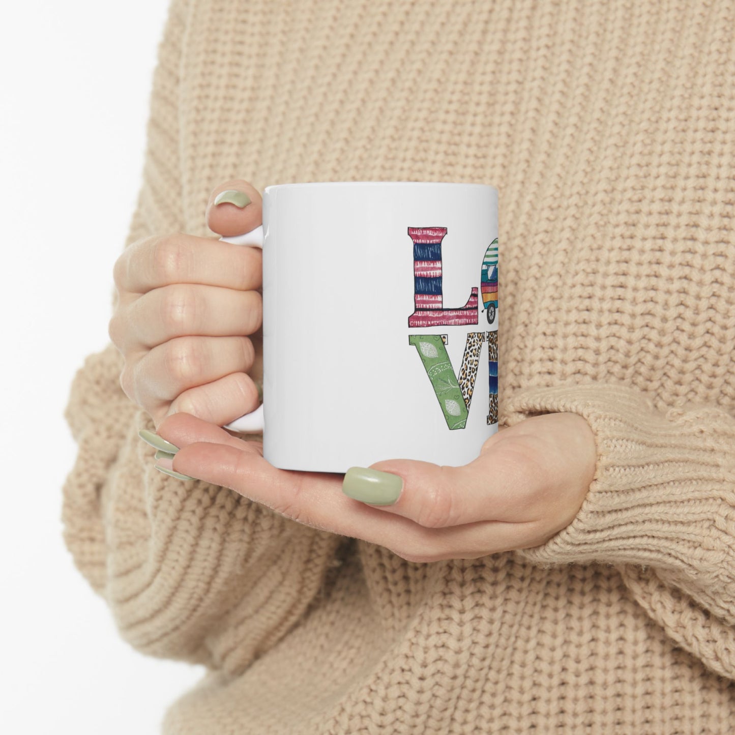 White mug with "LOVE" in a collage of patterned letters held by hands.