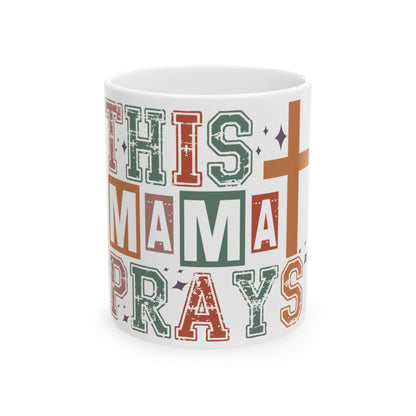 White mug with colorful text reading "THIS MAMA PRAYS" and a cross.