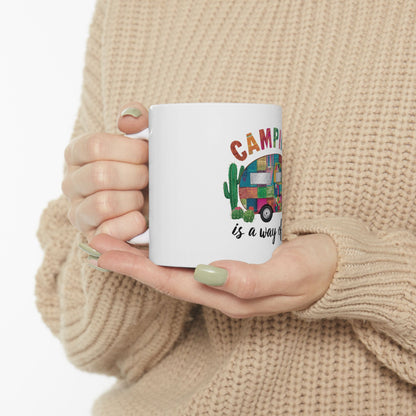 White mug with "Camping is a way of life" and colorful camper van design.
