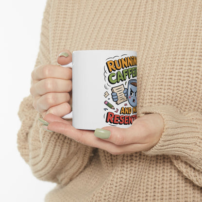 White mug with cartoon text "RUNNING ON CAFFEINE AND RESENTMENT".