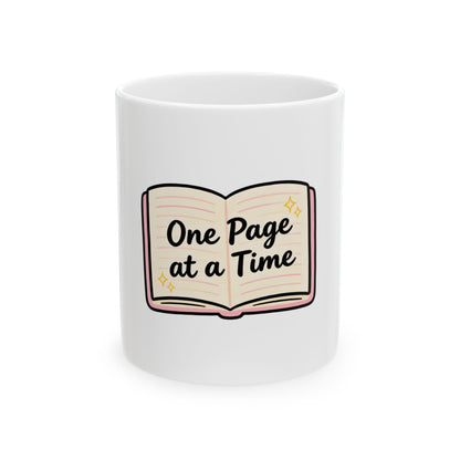 White mug with cartoon book illustration and text "One Page at a Time".