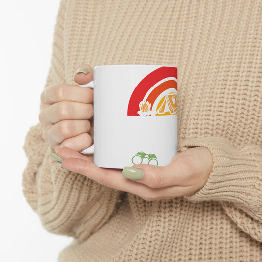 White mug with camping graphics: rainbow, tent, campfire, binoculars.