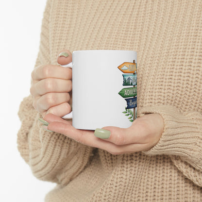 White mug with directional signs saying "Let the adventure begin".