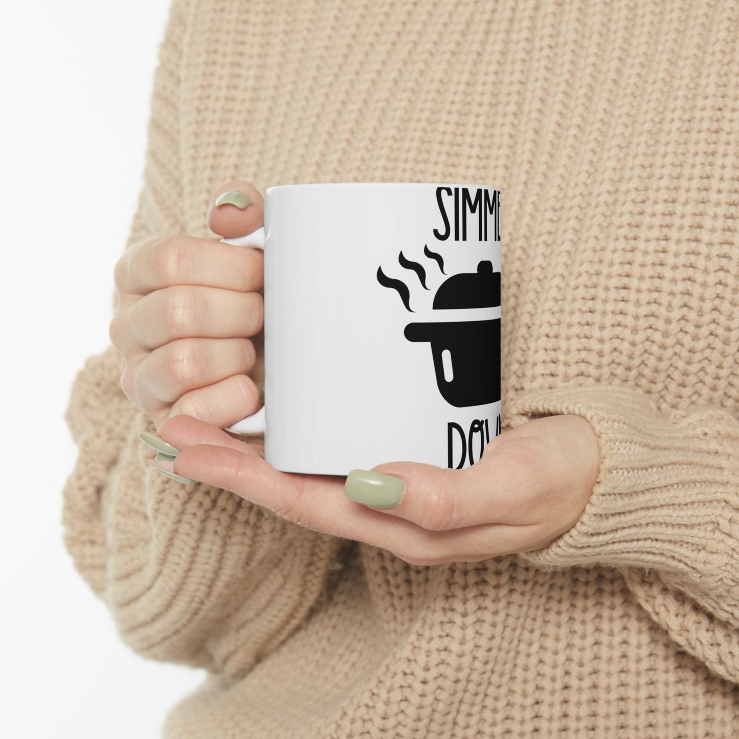 White mug held by hands, featuring a black pot graphic and "SIMMER DO" text.