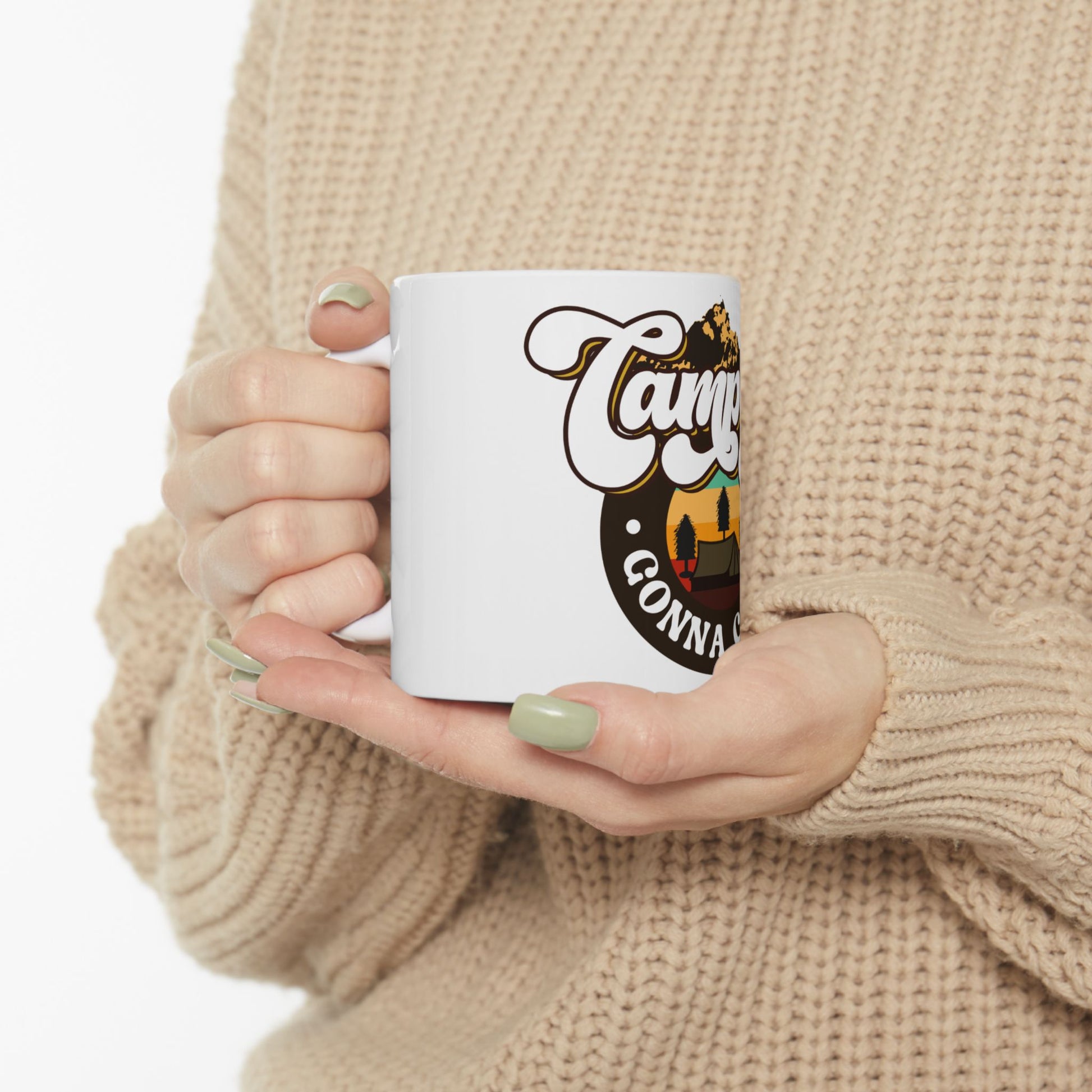 White mug with "Camp Gonna" text and a camping graphic held by hands.