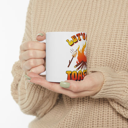 Mug with "Let's Toast" and a marshmallow on a stick over flames.