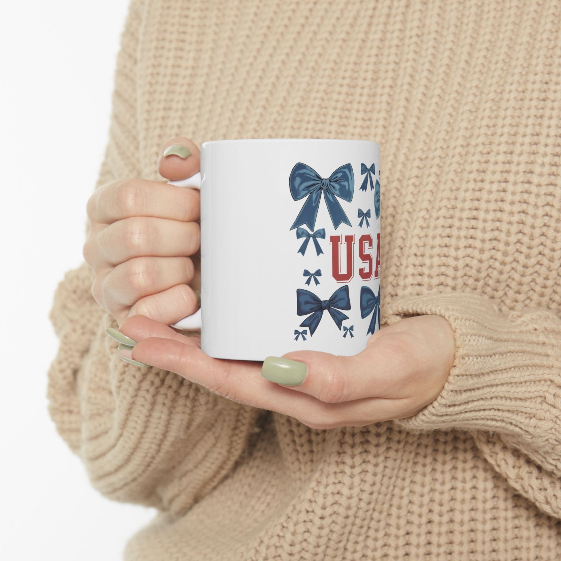 White mug with blue bows and "USA" text held by hands.