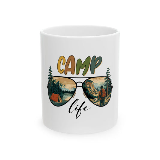 White mug with "CAMP life" text and sunglasses reflecting a mountain landscape.