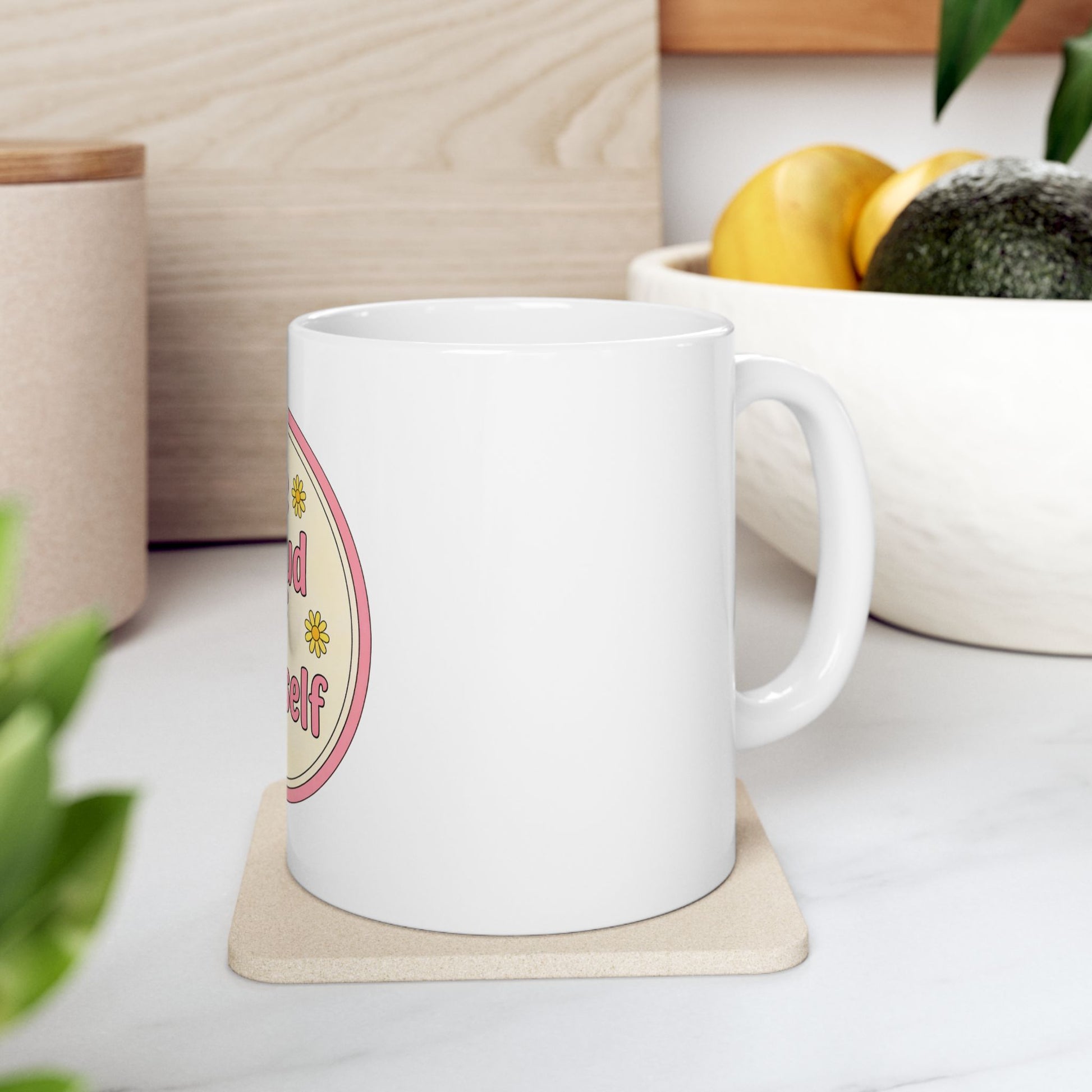 White mug with text "kind to yourself" and floral design on coaster.