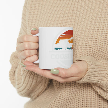 White mug with "COUSIN CREW" text and mountain sunset design.