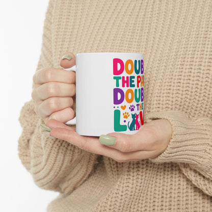 White mug with colorful text "DOUB THE PA THE LO" and a cat silhouette.