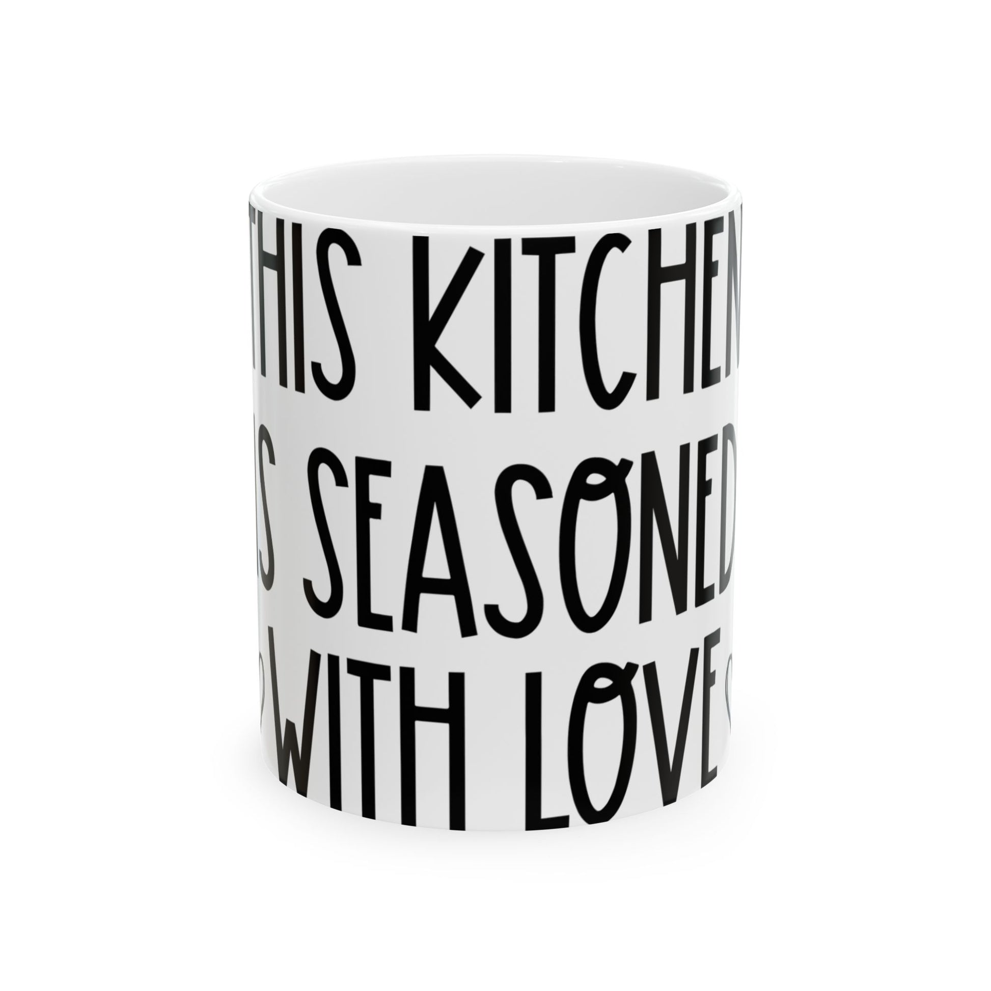 White mug with black text reading "IN THIS KITCHEN IS SEASONED WITH LOVE".