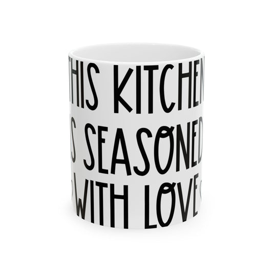 White mug with black text reading "IN THIS KITCHEN IS SEASONED WITH LOVE".