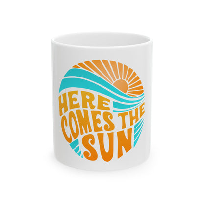 White mug with "Here Comes the Sun" text and a sun and wave graphic.