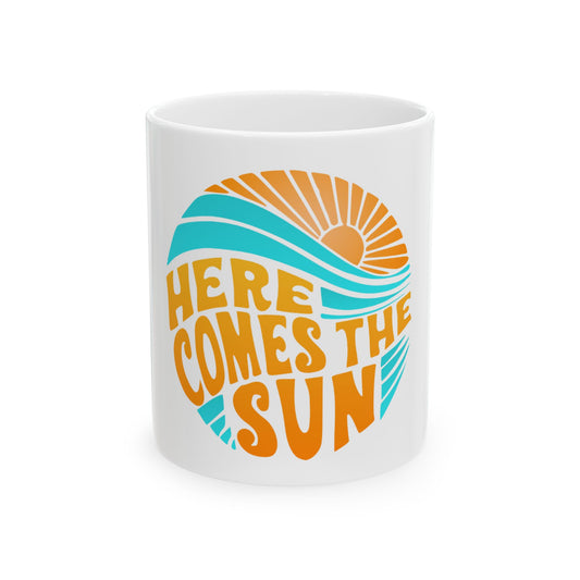 White mug with "Here Comes the Sun" text and a sun and wave graphic.