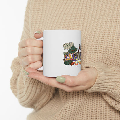 White mug with camping-themed illustrations and text, held by a person.