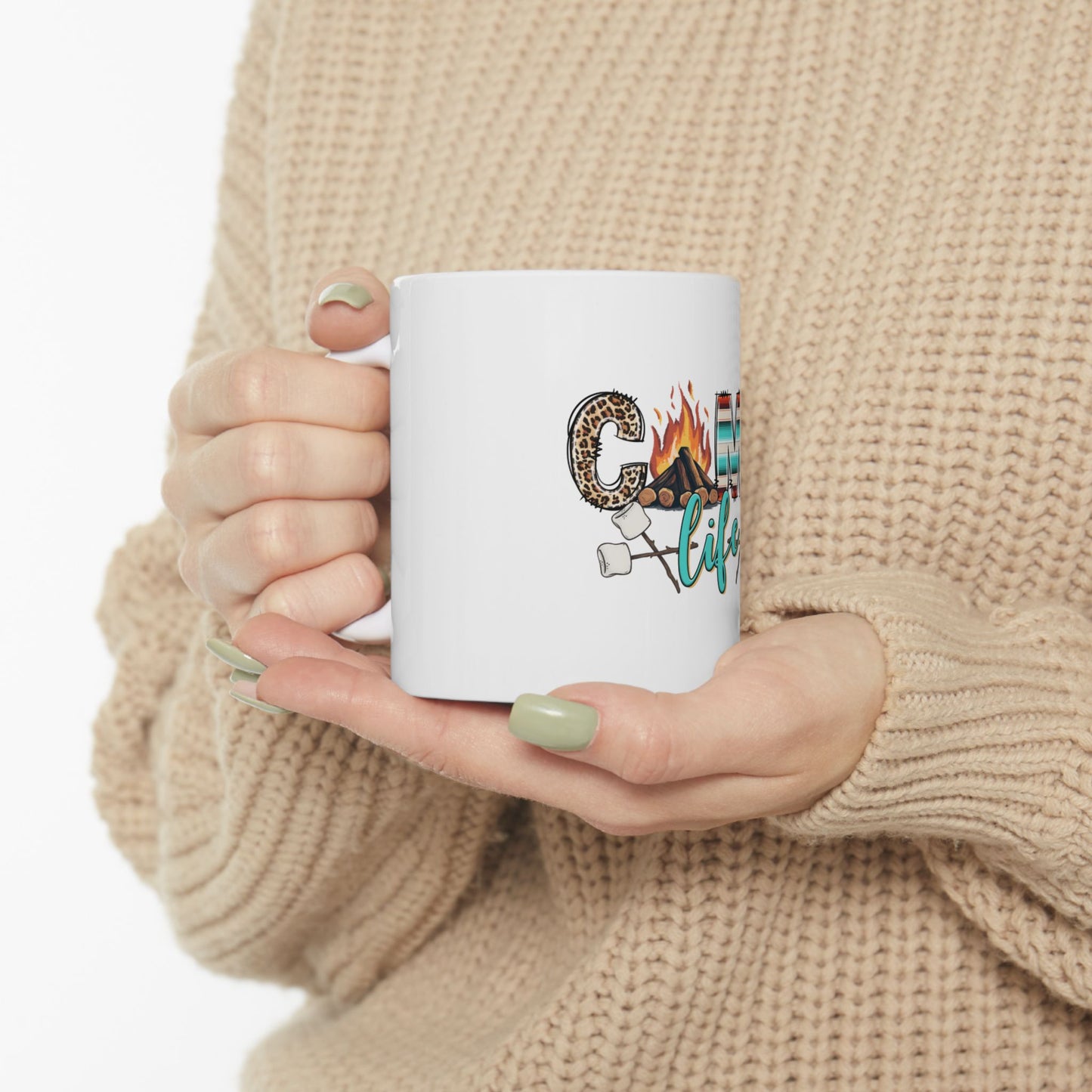 White mug with "Camp life" text and marshmallow graphics held by hands.