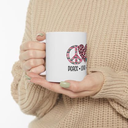 White mug with "PEACE LOVE" text and pink leopard print heart graphic.