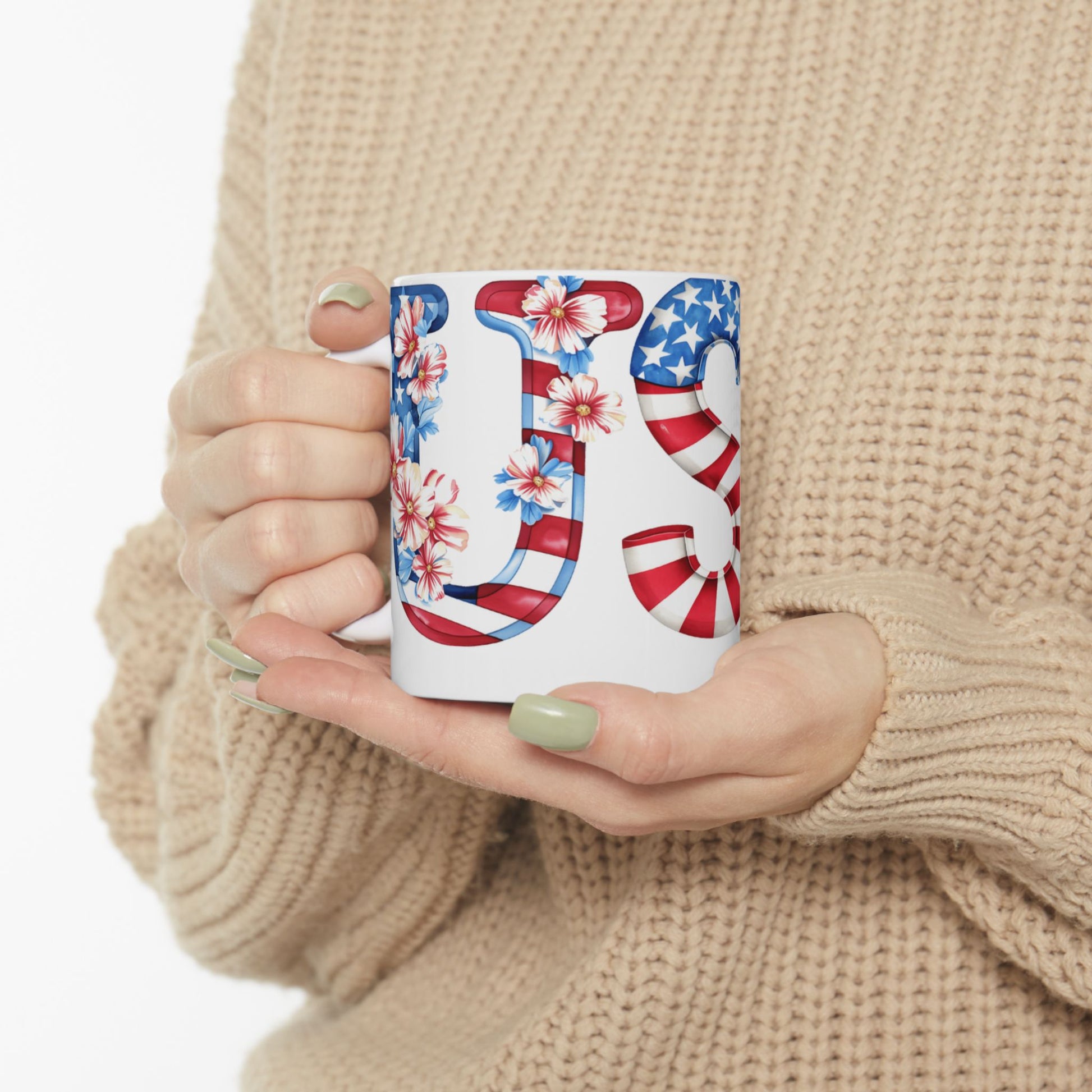 White mug with "US" design in American flag and floral pattern held by hands.