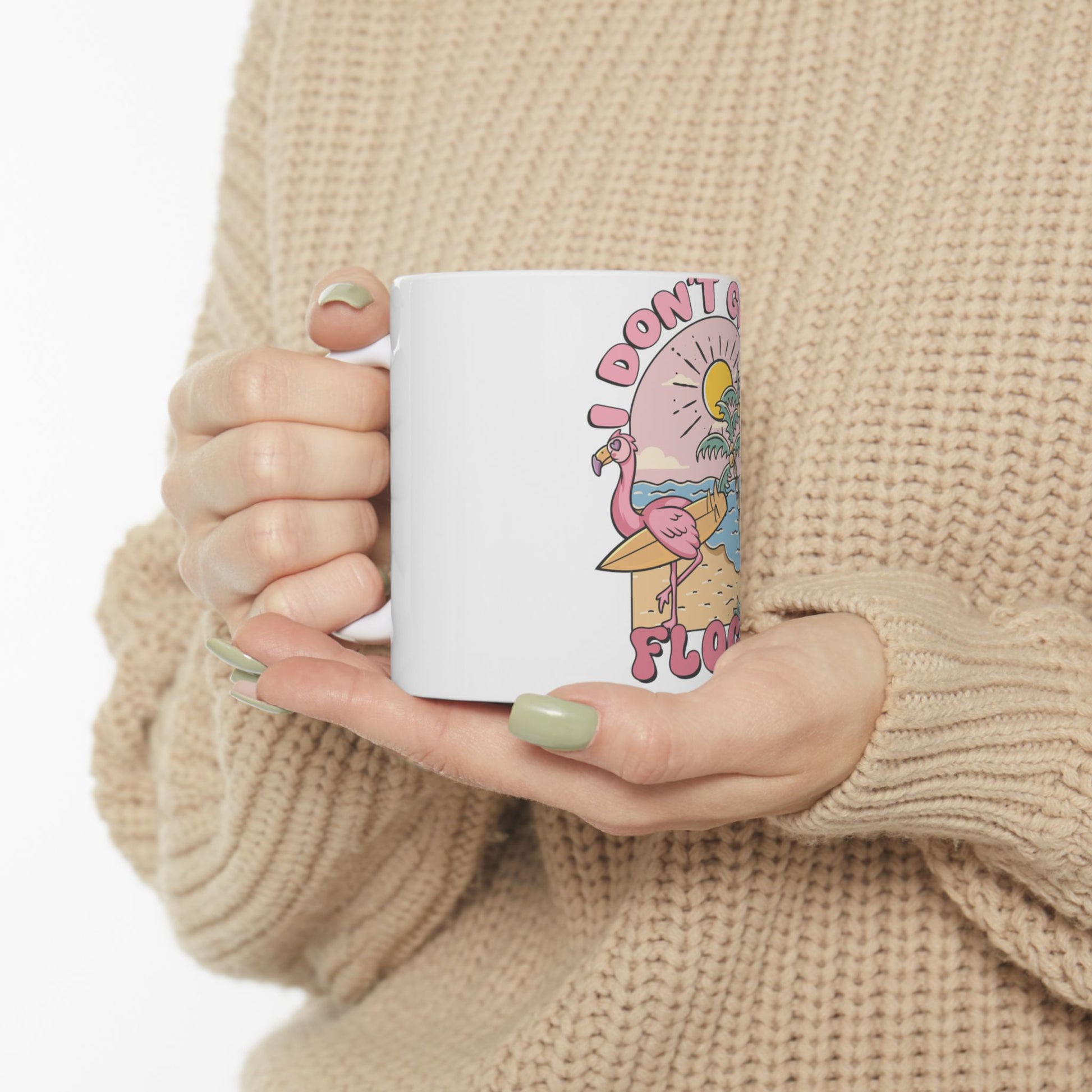 White mug with "I DON'T GAF" text and a flamingo surfing a wave.