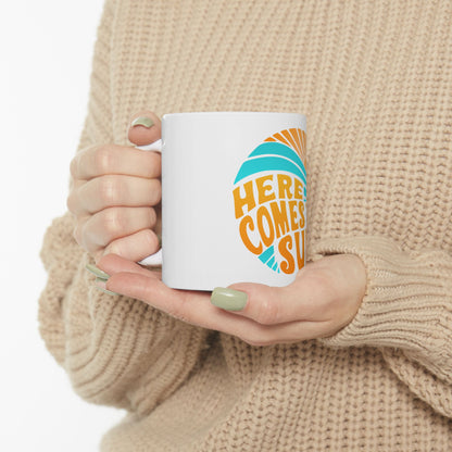 White mug with "HERE COMES SUN" text and a stylized sun graphic.