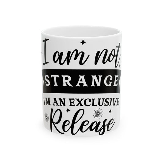 White mug with black text "I am not STRANGE I'M AN EXCLUSIVE Release".