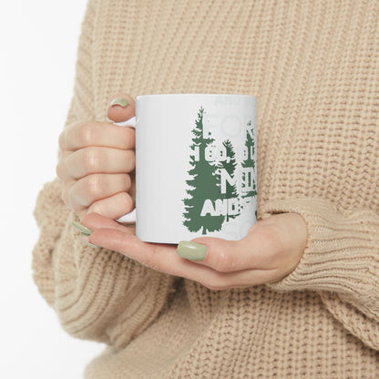 White mug with "Forest vibes" and trees design, held by hands.