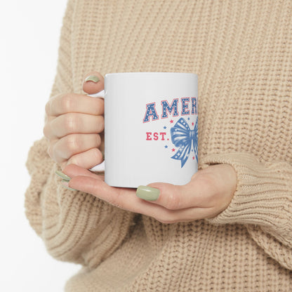 White mug with "AMER EST." and a red, white, and blue bow graphic.