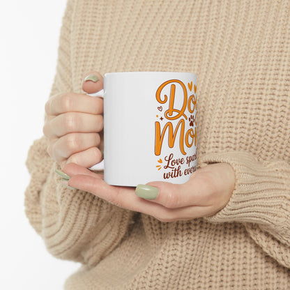 White mug with "Dog Mom" and "Love sparks with every" text, held by hands.