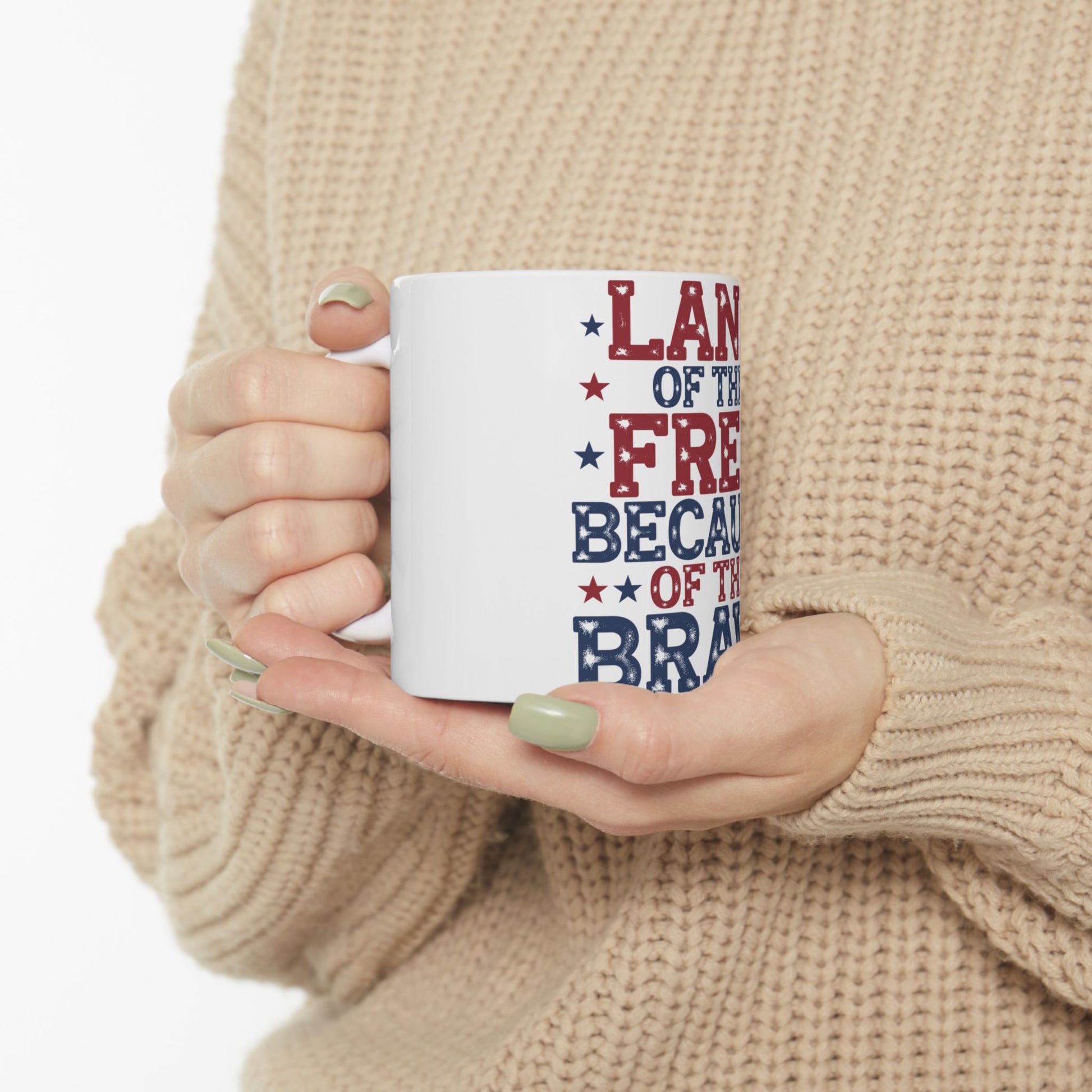 White mug with red and blue text "LAND OF THE FREE BECAUSE OF THE BRAVE".