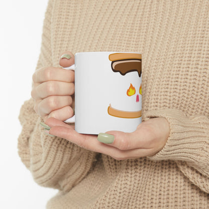 White mug with s'mores graphic, held by hands in a cream sweater.
