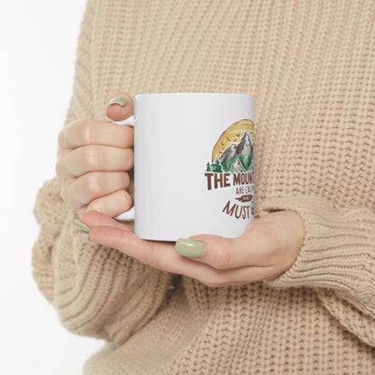 White mug with "The mountains are calling" and trees design.