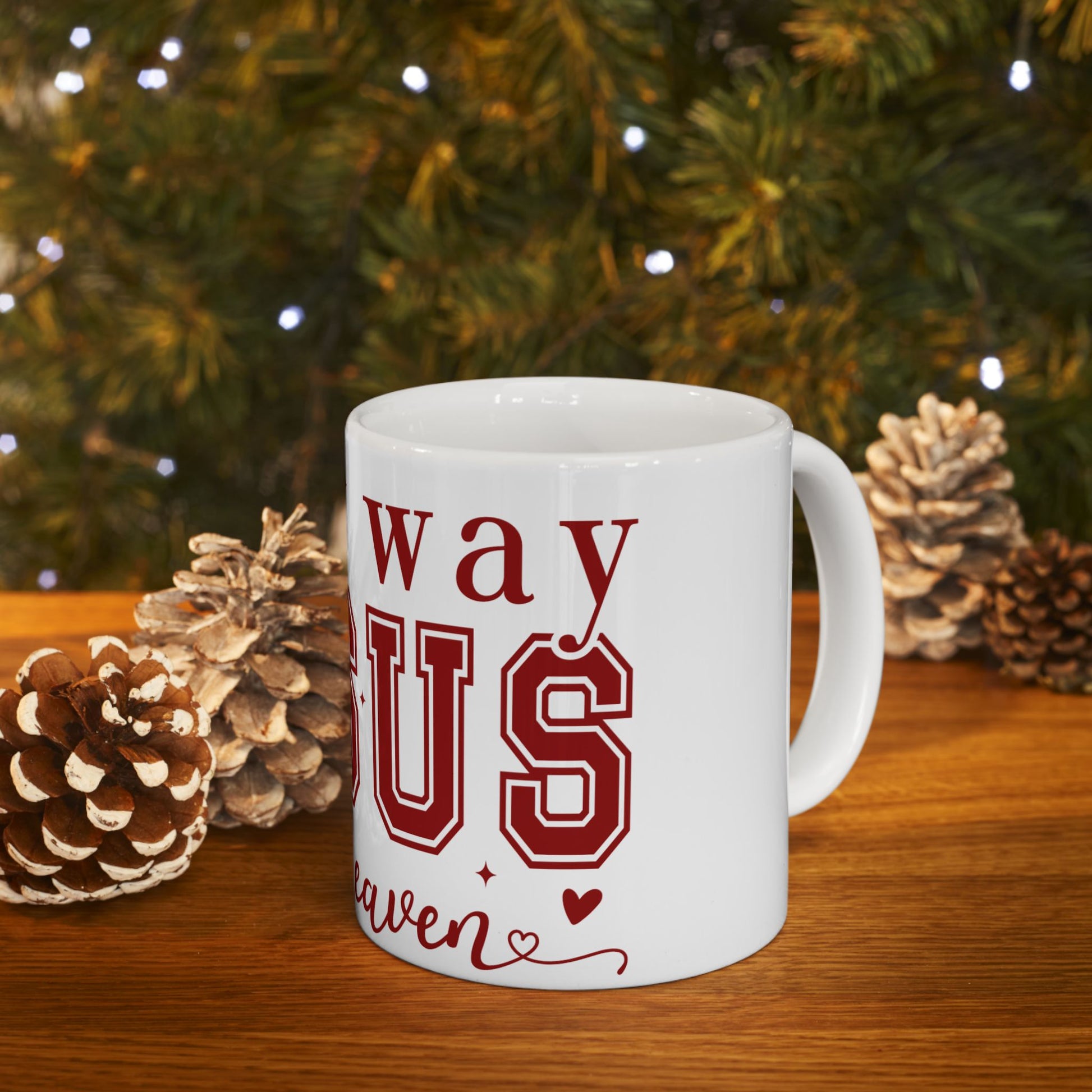 White mug with "Way US" in red text, set on a wooden surface with pinecones.