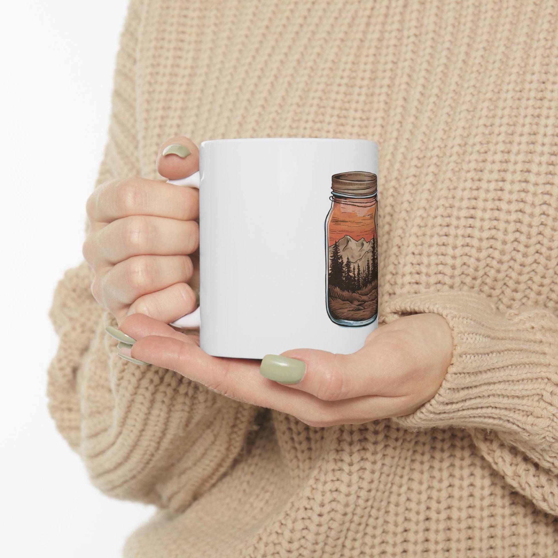 White mug with a forest and mountain landscape design within a jar.