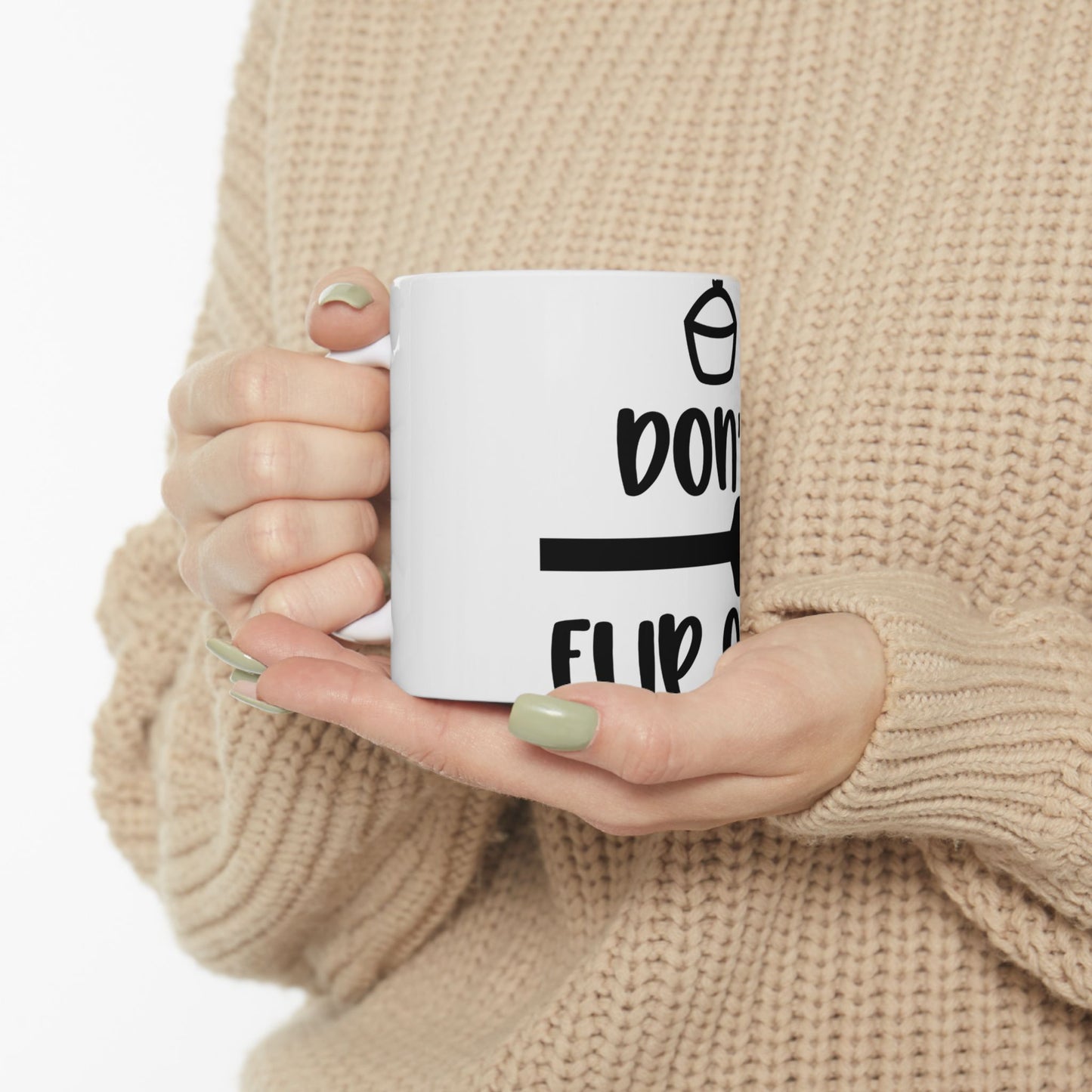 White mug held by person, showing "don't flip" text with an arrow.