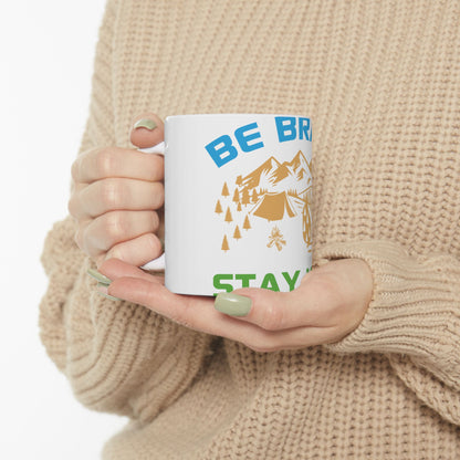 White mug with "BE BRAVE STAY WILD" and camping graphic.