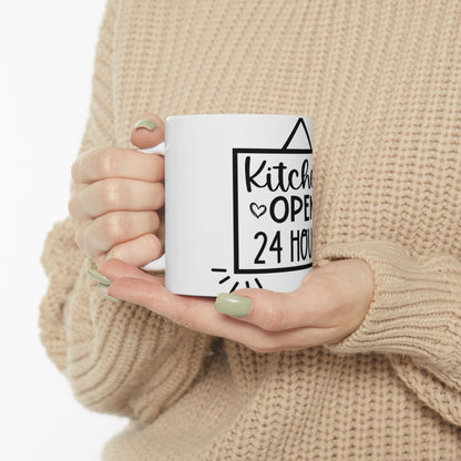 White mug held by hands with text "Kitchen OPEN 24 HOURS".