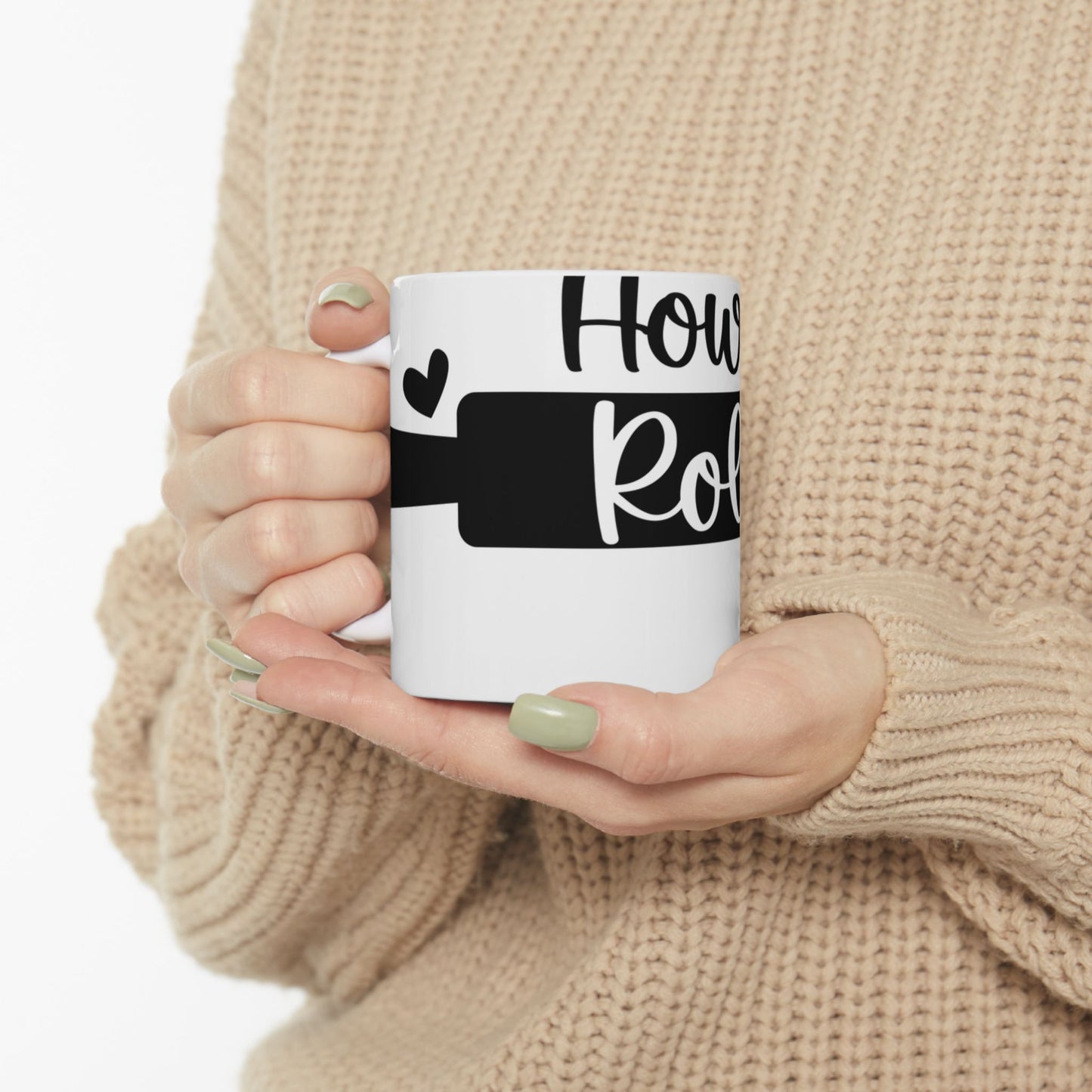 White mug with "How Roll" text and heart design held by person.