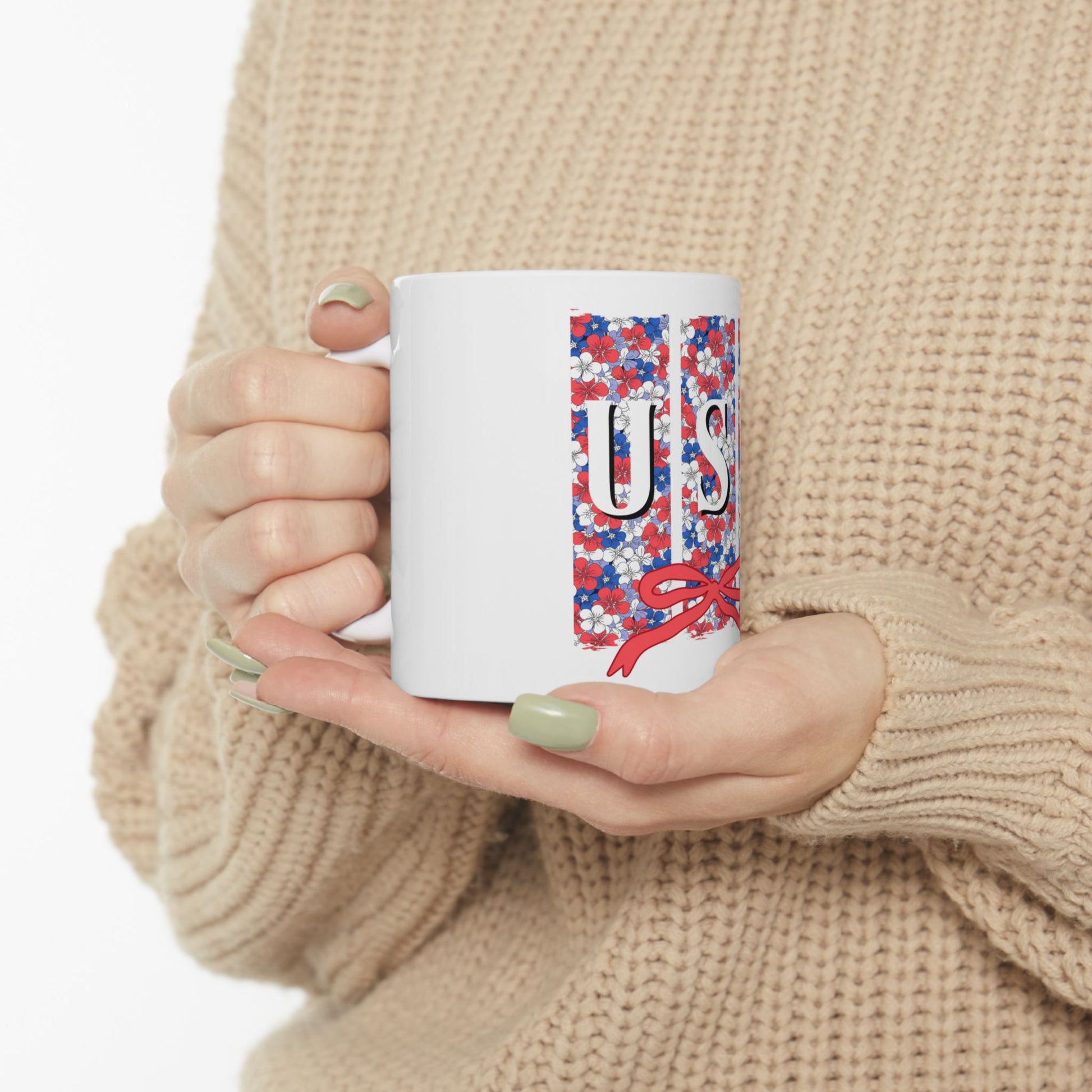 White mug with red, white, and blue floral pattern and red bow.