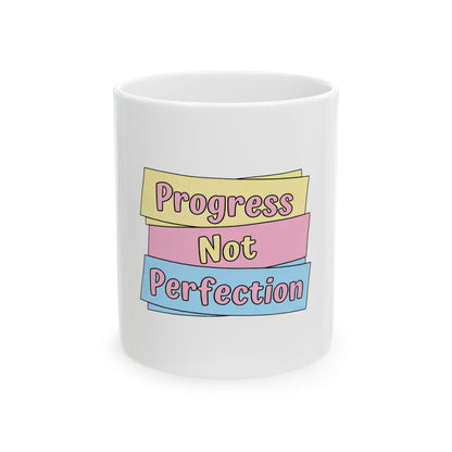 White mug with "Progress Not Perfection" text on pastel ribbons.