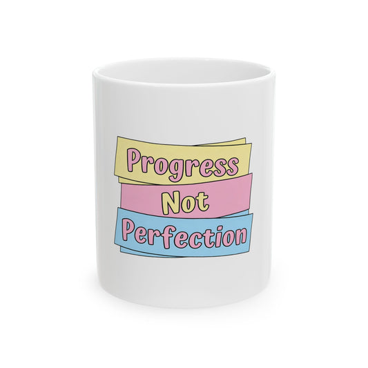 White mug with "Progress Not Perfection" text on pastel ribbons.