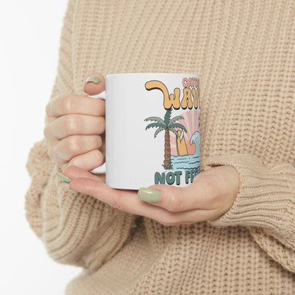 White mug with "Catch waves not feelings" and a palm tree illustration.