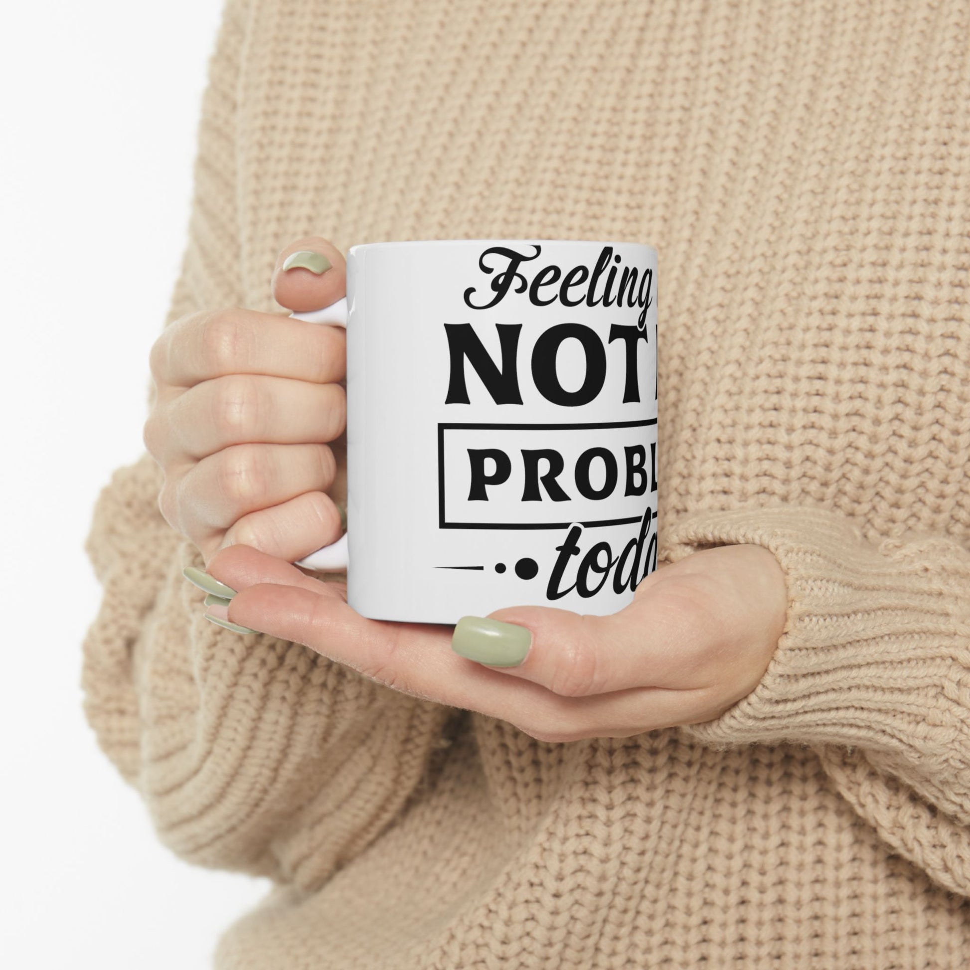 White mug with black text "Feeling Not Problem... today" held by hands.