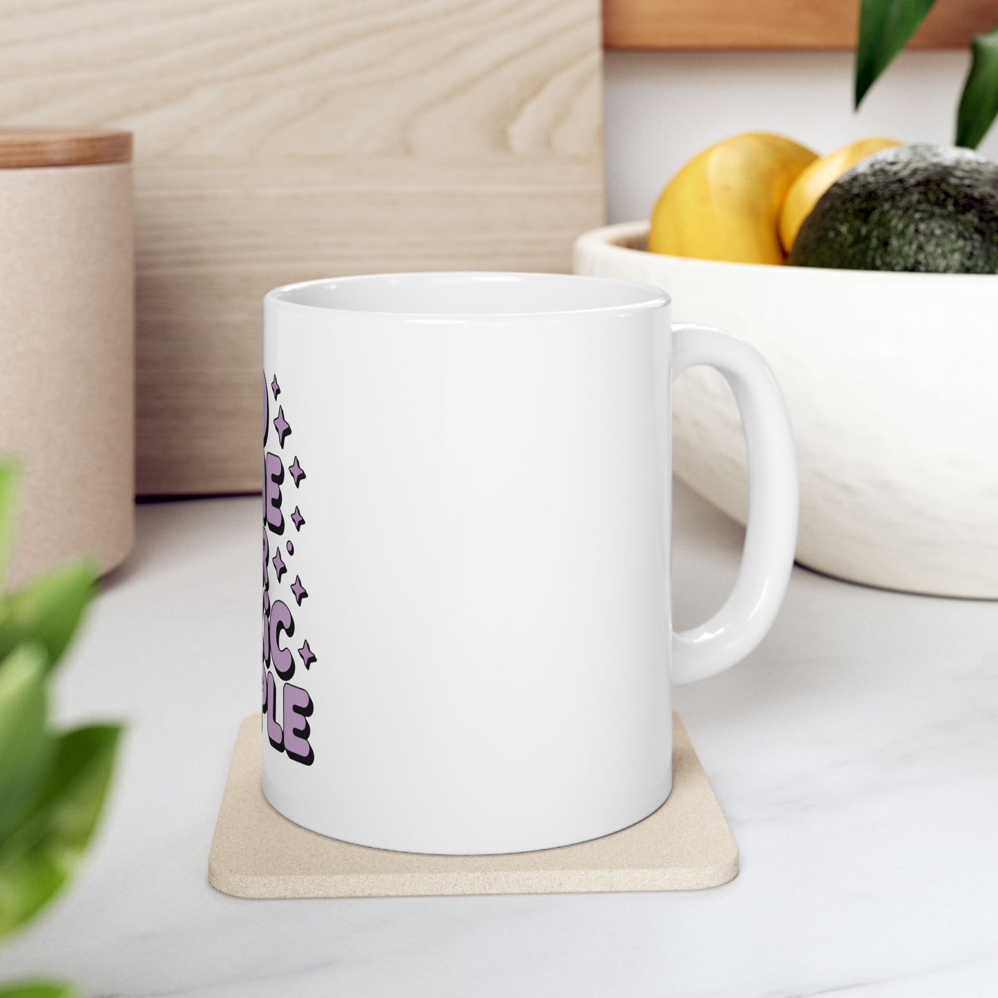 White mug with "Be The Magic" text in purple lettering.